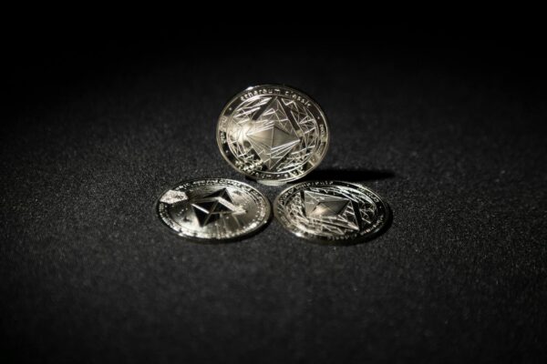 Close-up of three Ethereum coins on a dark background, showcasing digital currency themes.
