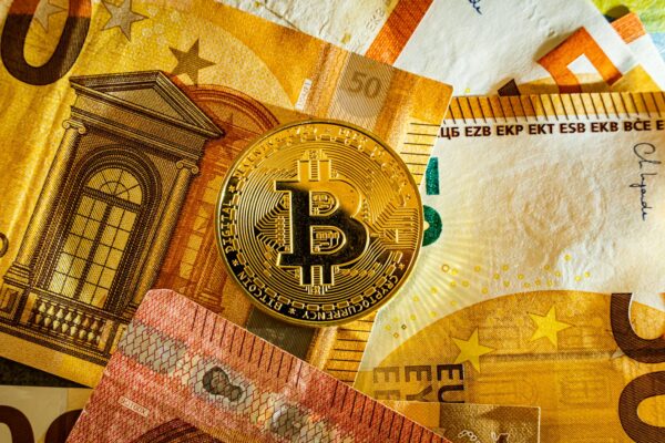 Golden Bitcoin coin placed on euro banknotes symbolizing digital currency and modern finance.